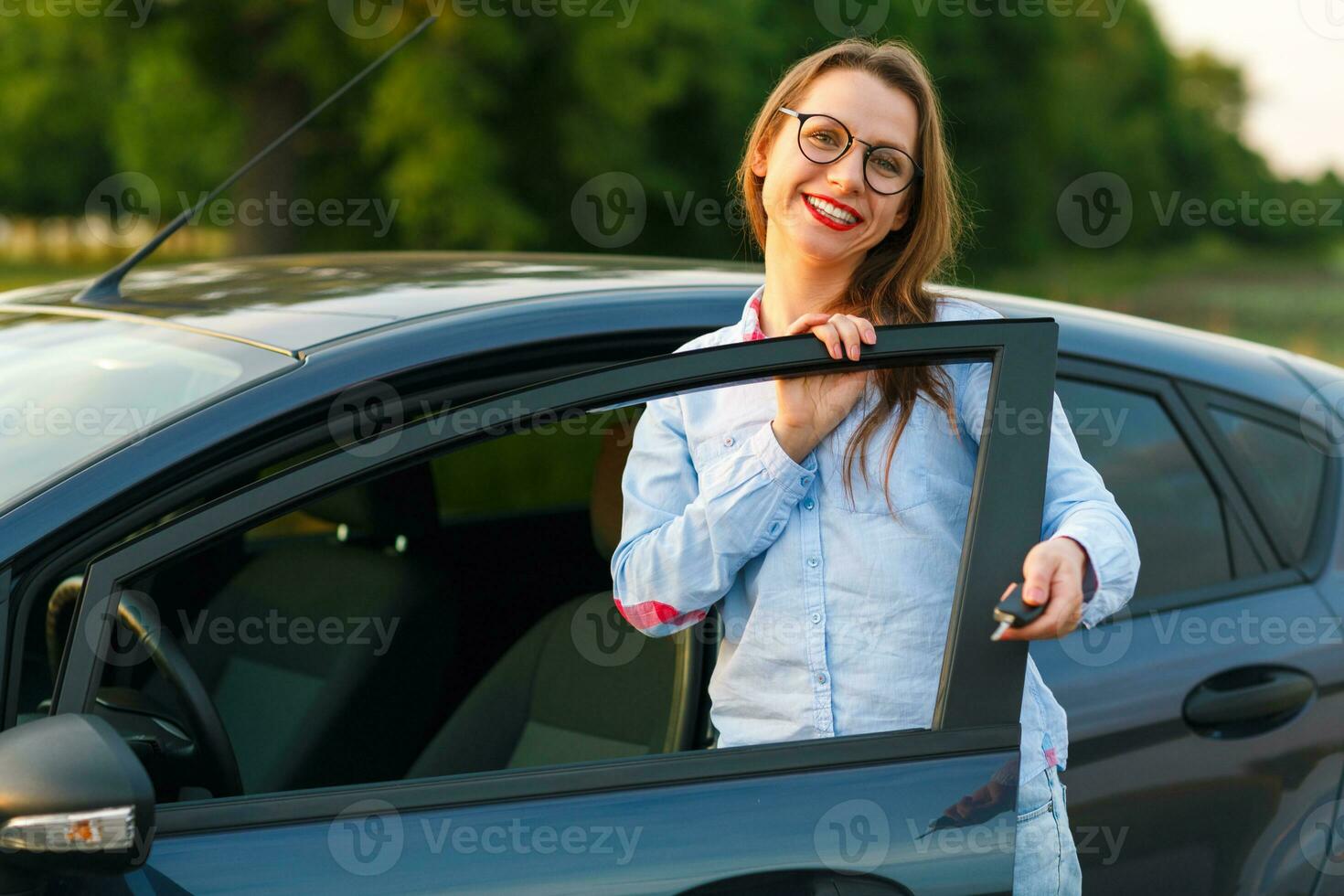 Young woman standing near a car with keys in hand photo