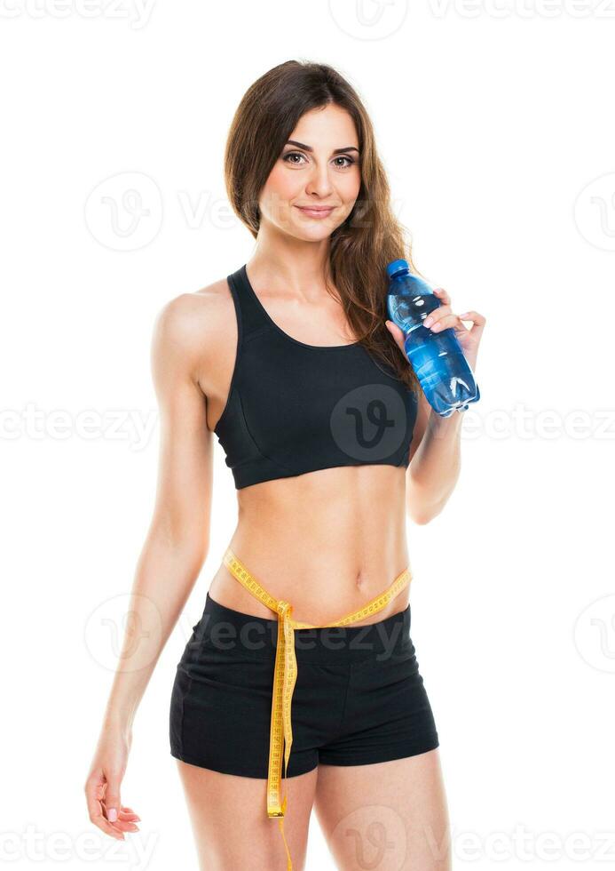 Woman measuring perfect shape of beautiful thigh with bottle of water photo