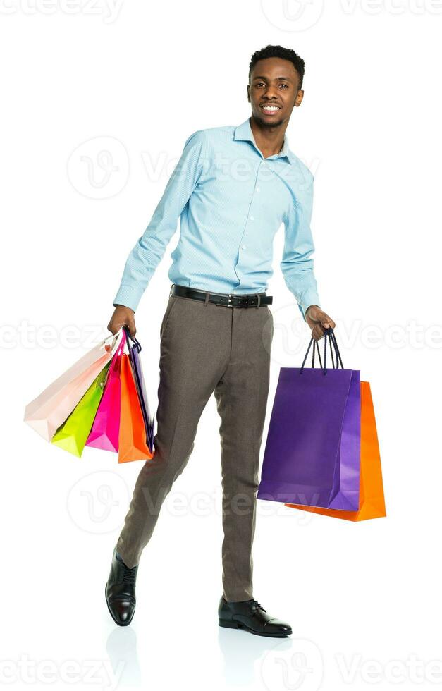 Happy african american man holding shopping bags on white background photo
