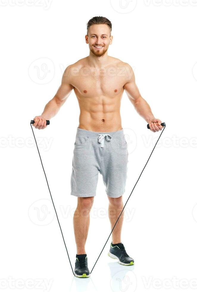 Athletic attractive man jumping on a rope on the white photo