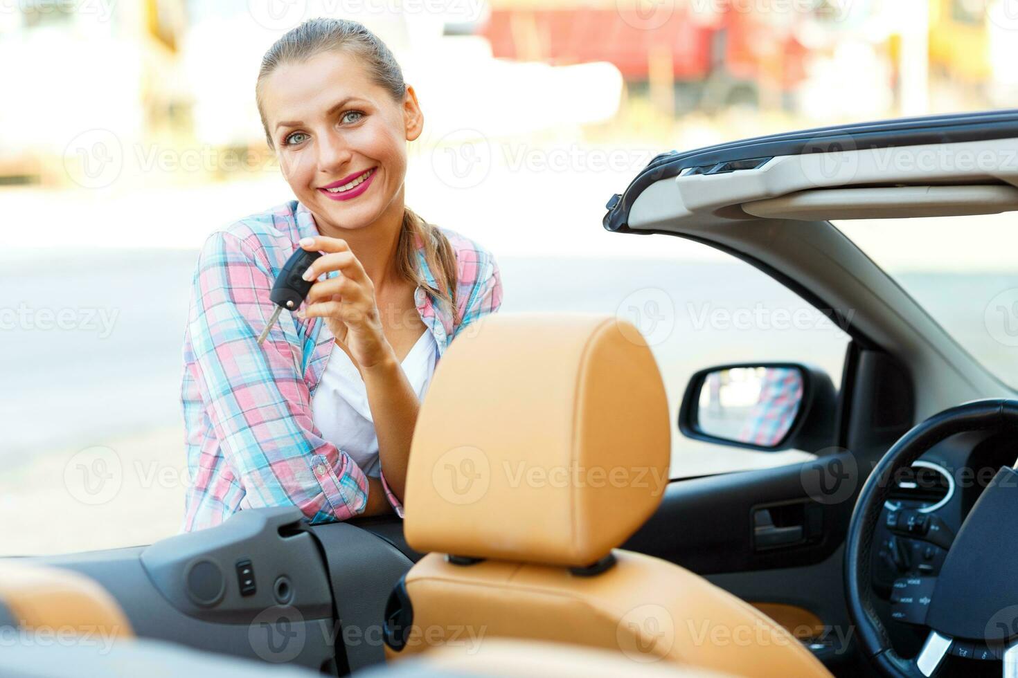 joven mujer en pie cerca un convertible con llaves en mano foto