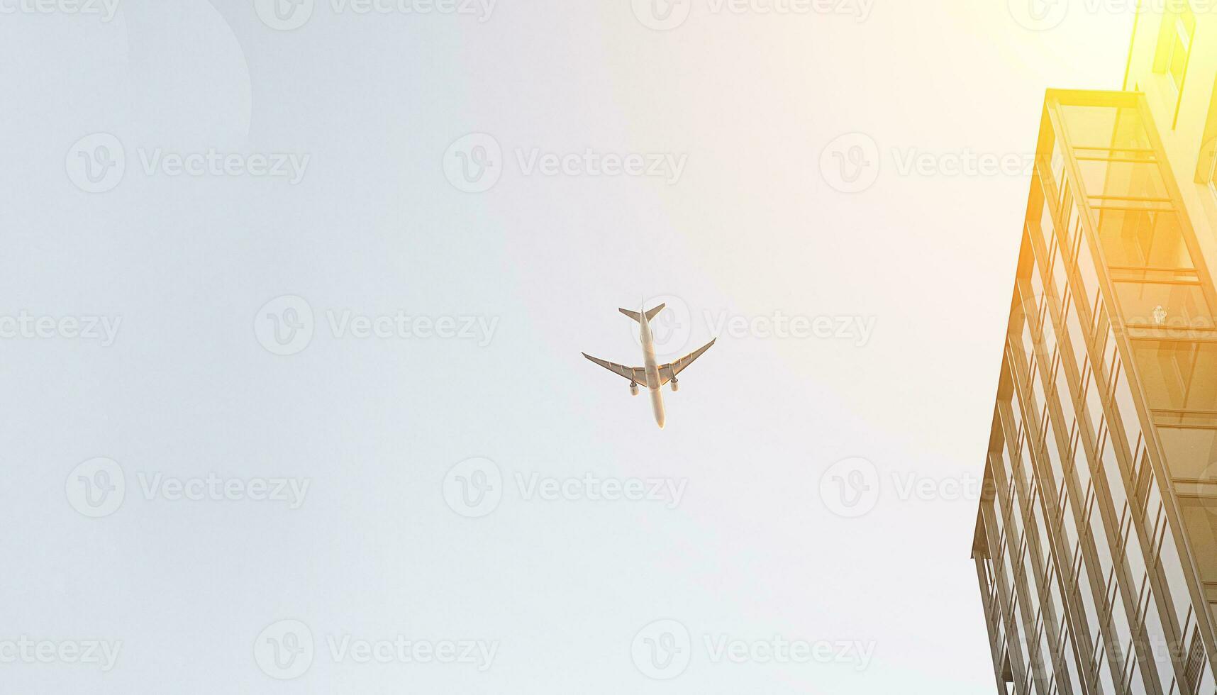 The passenger airplane is flying to land at the airport above the city, on sunset photo