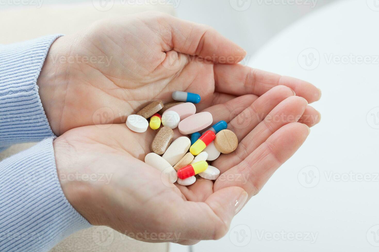 Many pills in woman hands. closeup on white background, macro selective focus. photo