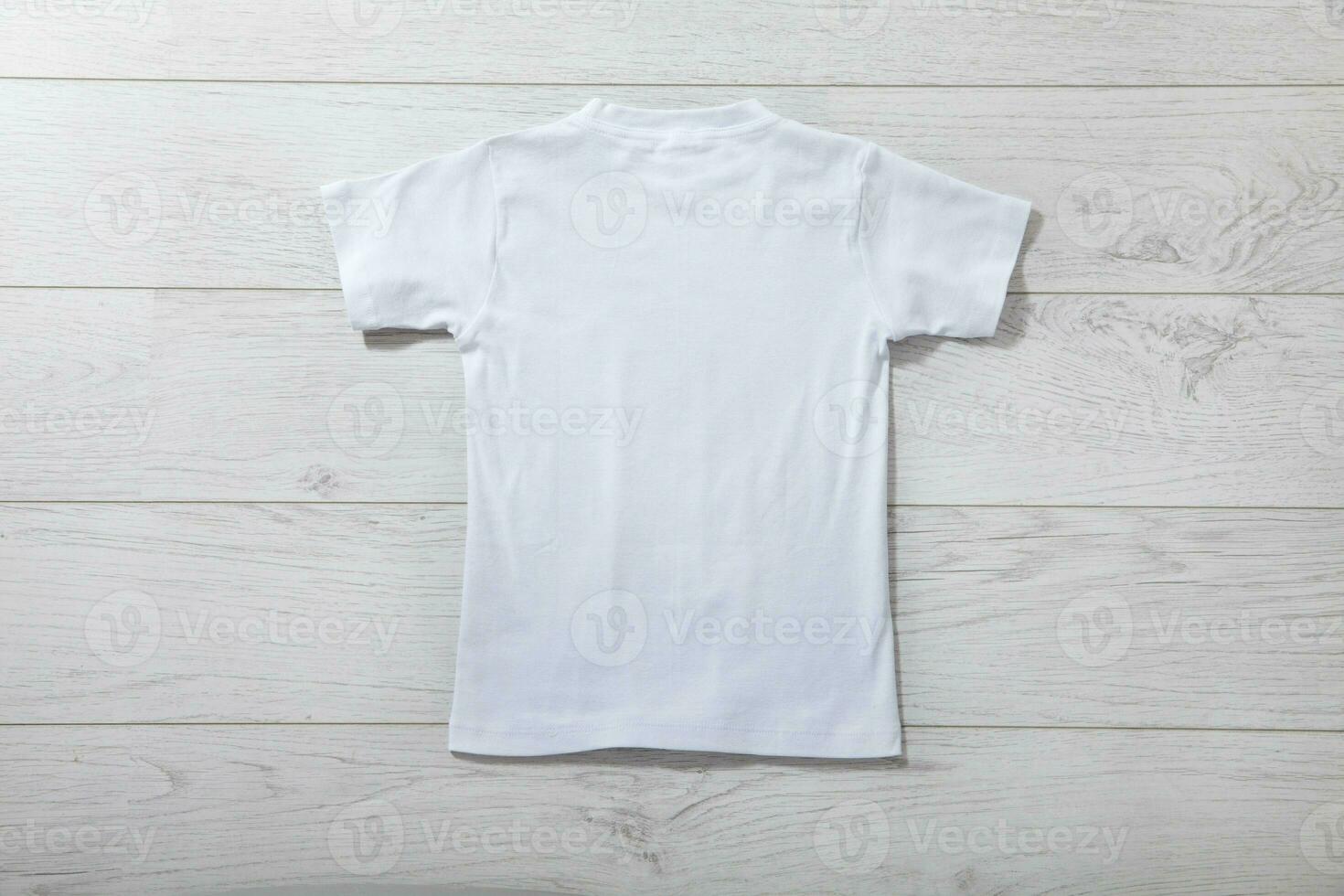 Back views on boys t-shirts on white wooden desk background. Mockup for design closeup photo