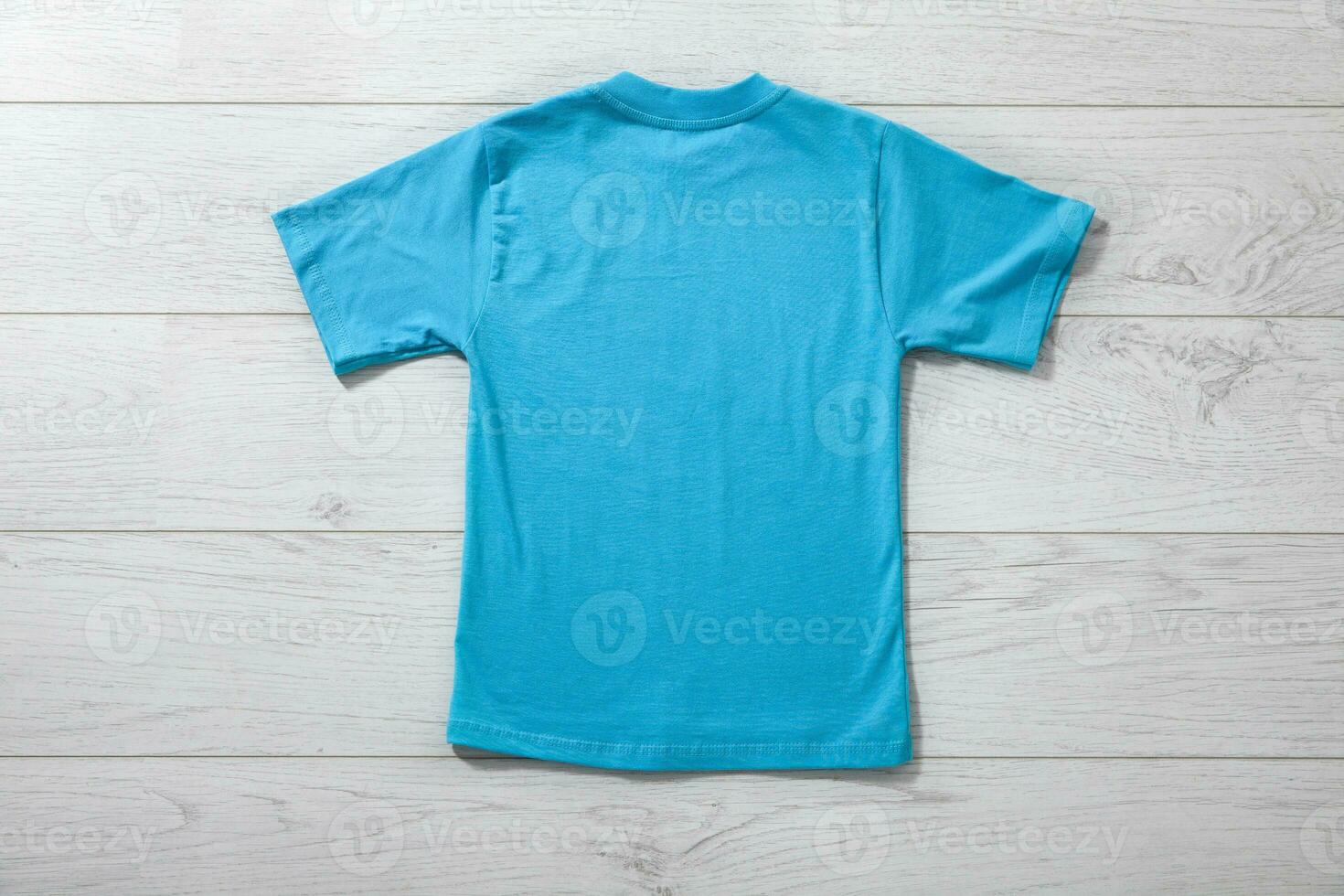 Back views on boys t-shirts on white wooden desk background. Mockup for design closeup photo