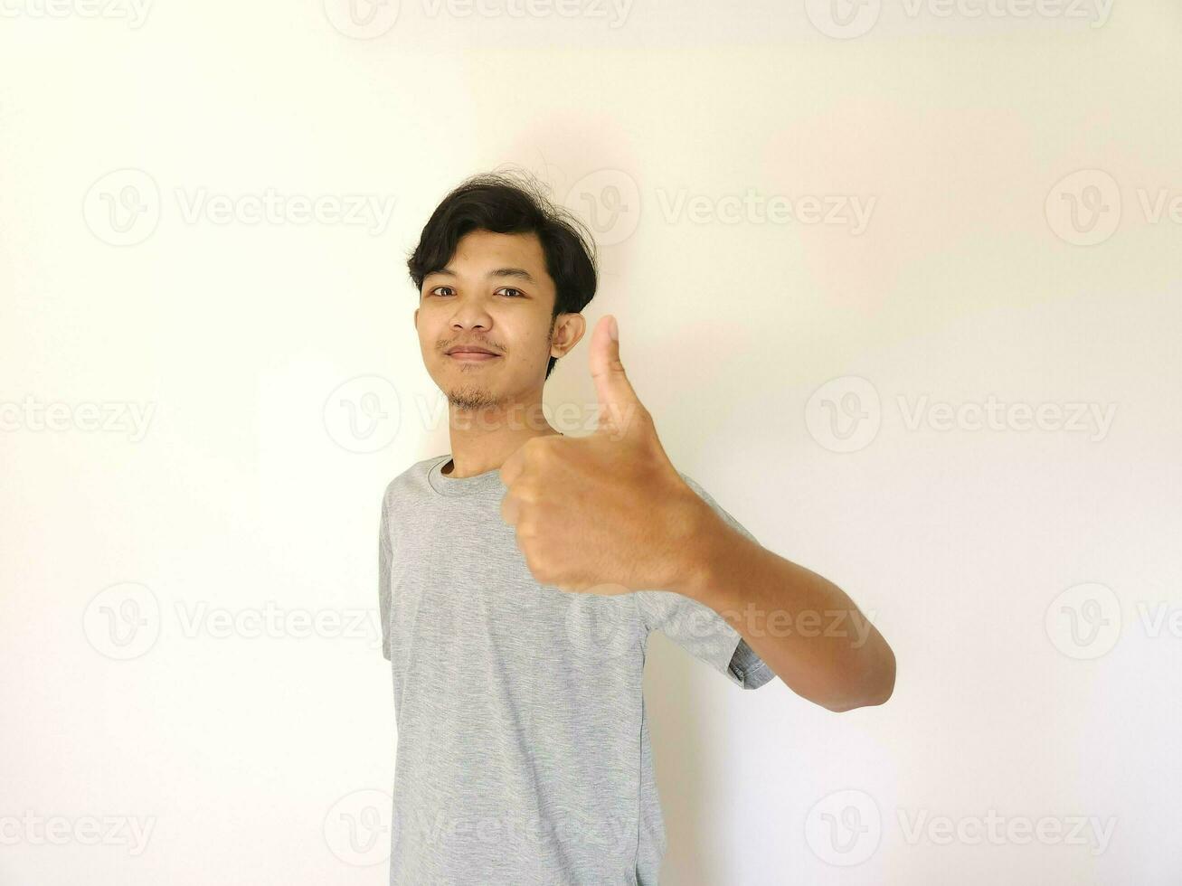 contento asiático hombre muestra pulgar arriba como un bueno mano firmar aislado en blanco antecedentes foto