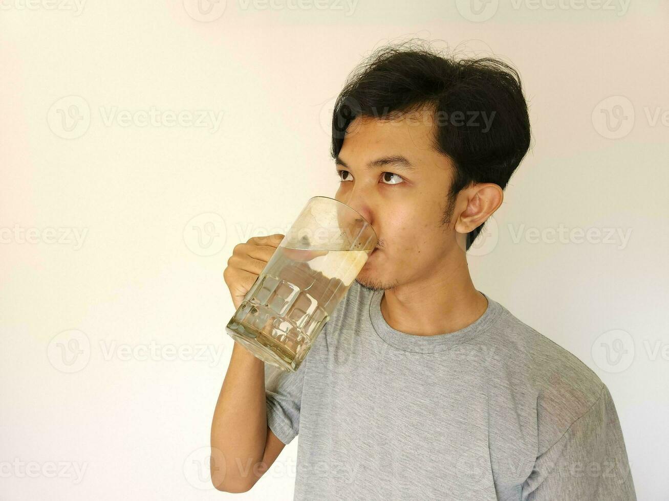 asiático hombre Bebiendo un vaso de agua foto