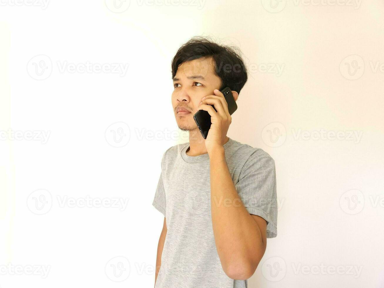 Asian young man on the phone with a smartphone isolated on white photo