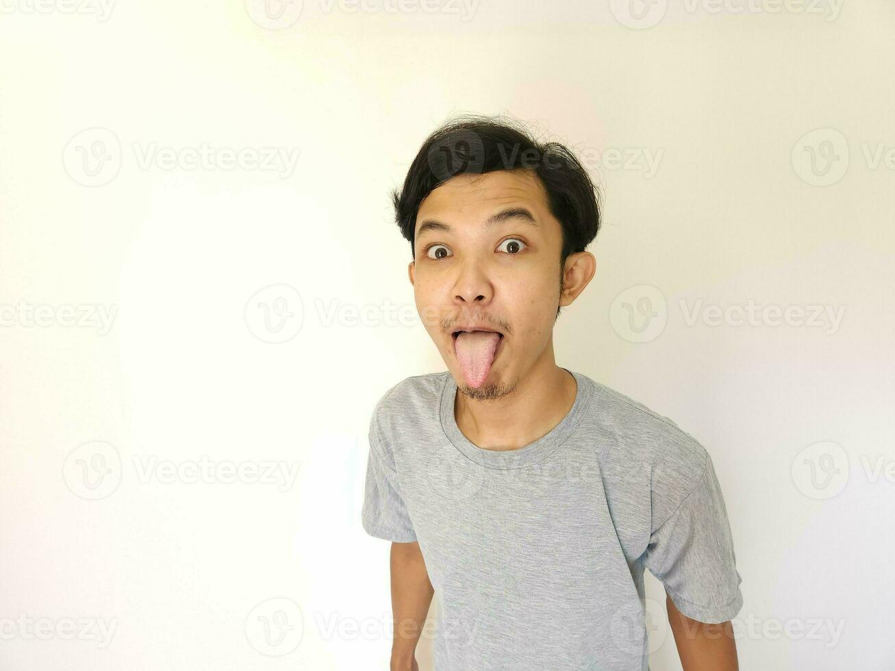 Funny tease and bully face of Asian man. sticking out tongue isolated on white photo