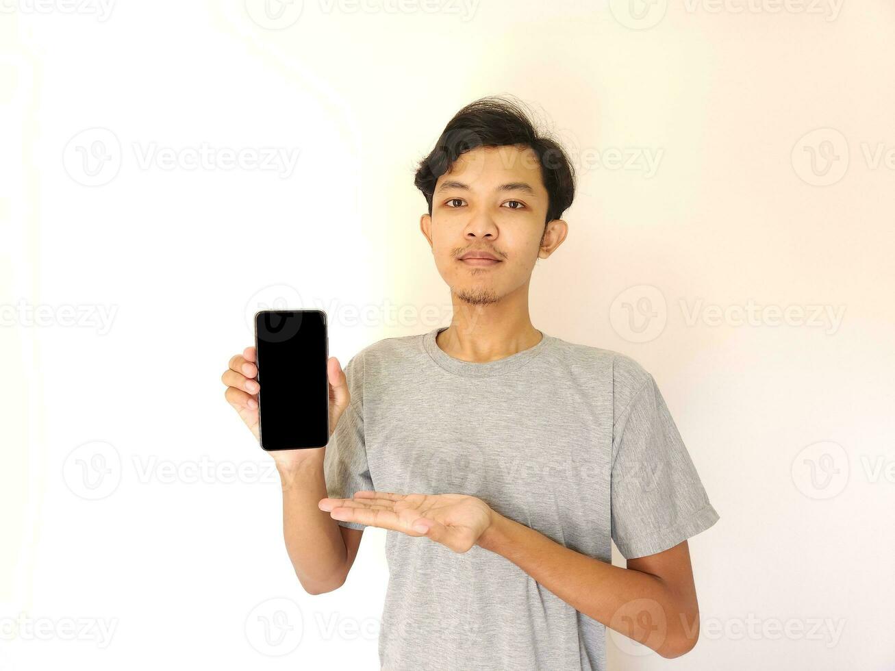 Asian young man showing smartphone with blank screen photo