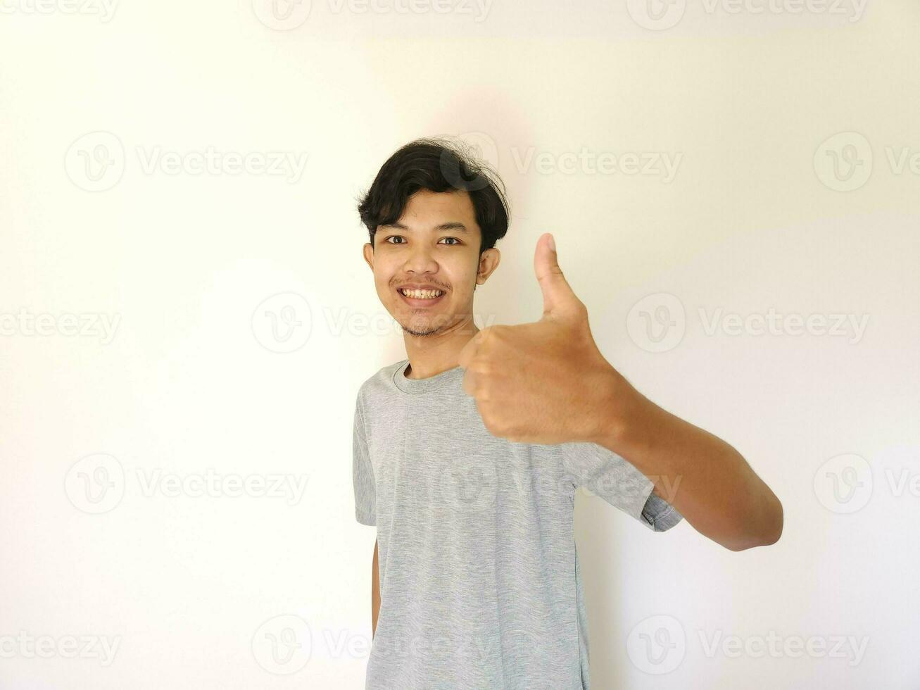 Happy asian man shows thumb up as a good hand sign isolated on white background photo