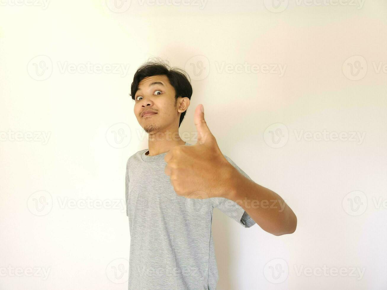 Happy asian man shows thumb up as a good hand sign isolated on white background photo