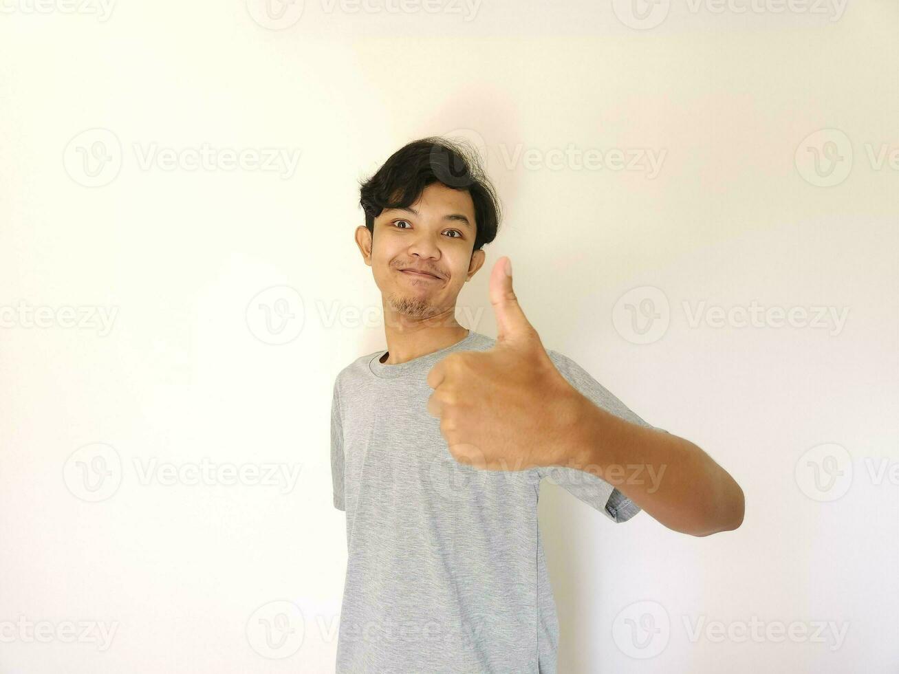contento asiático hombre muestra pulgar arriba como un bueno mano firmar aislado en blanco antecedentes foto