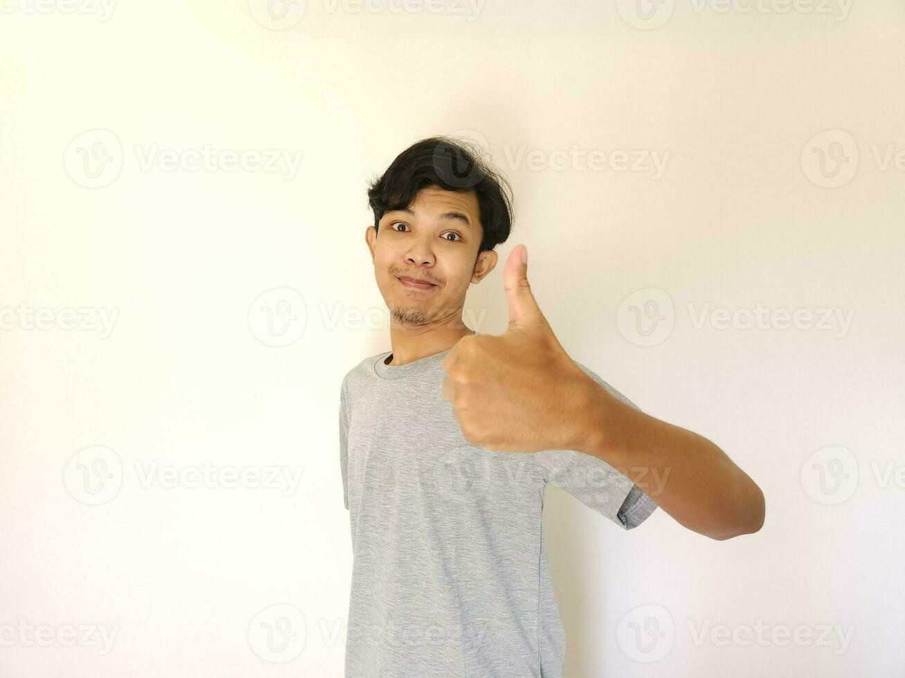 Happy asian man shows thumb up as a good hand sign isolated on white background photo