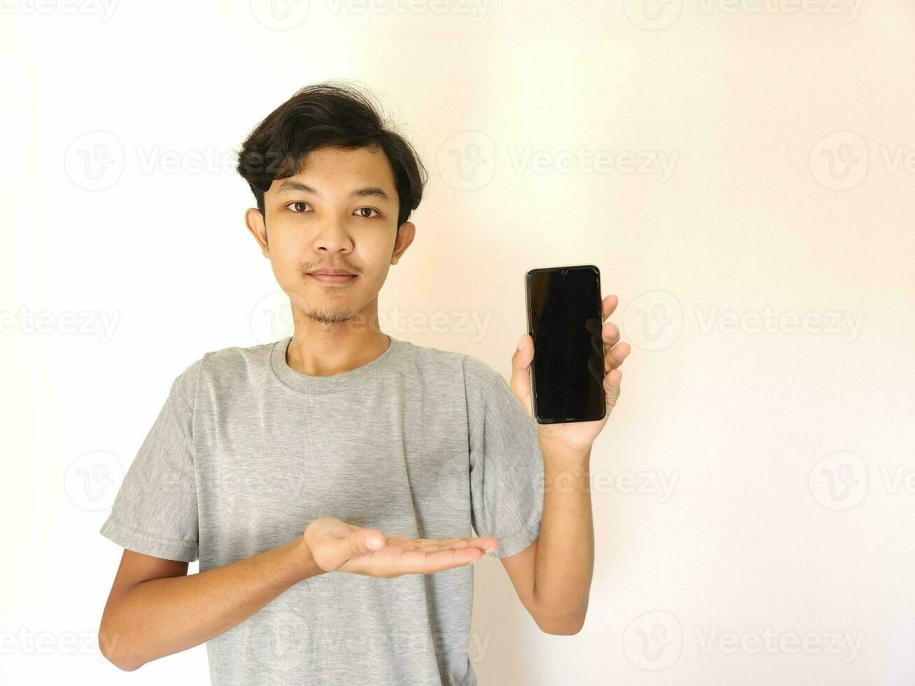 Asian young man showing smartphone with blank screen photo