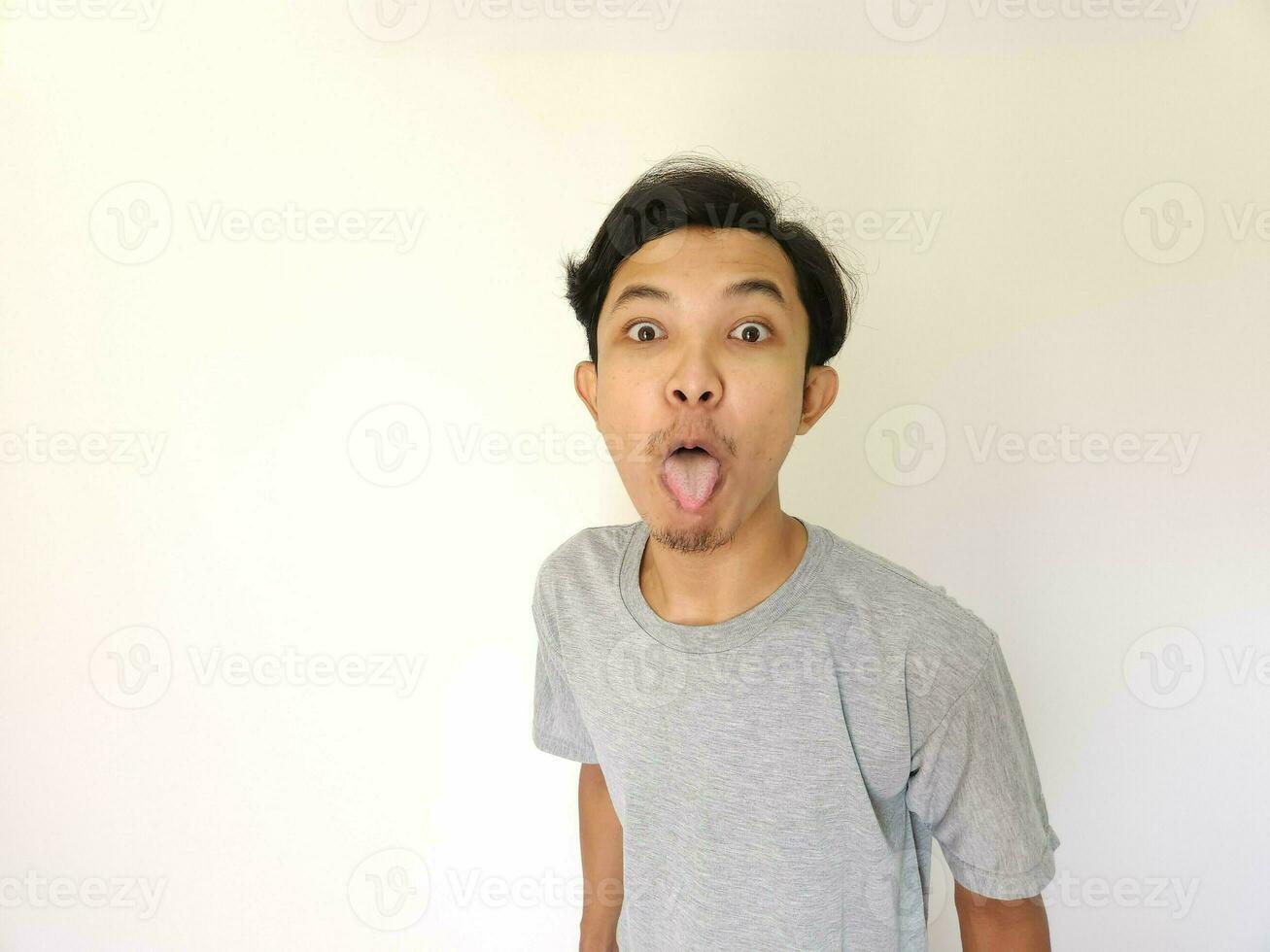 Funny tease and bully face of Asian man. sticking out tongue isolated on white photo