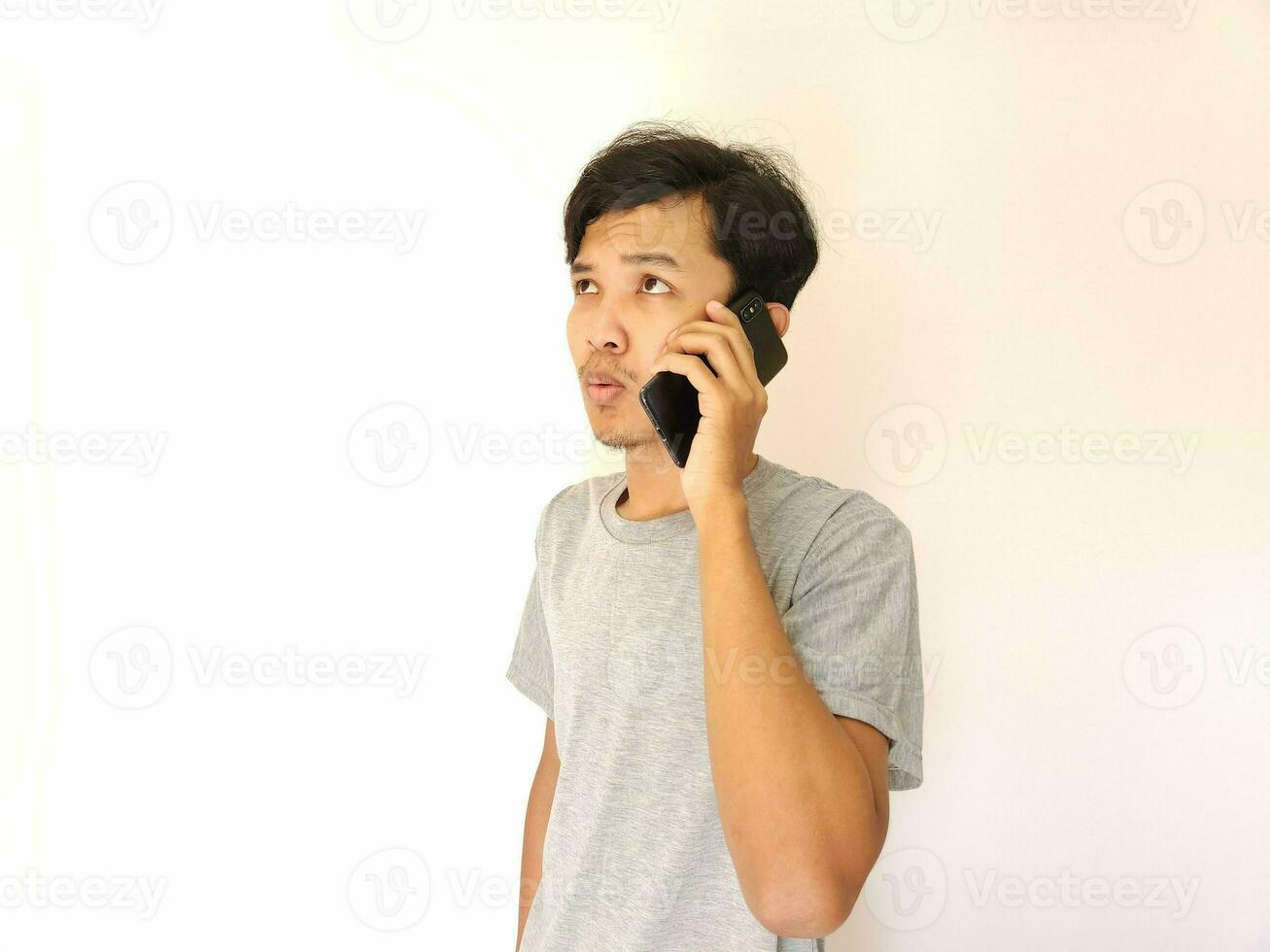 asiático joven hombre en el teléfono con un teléfono inteligente aislado en blanco foto