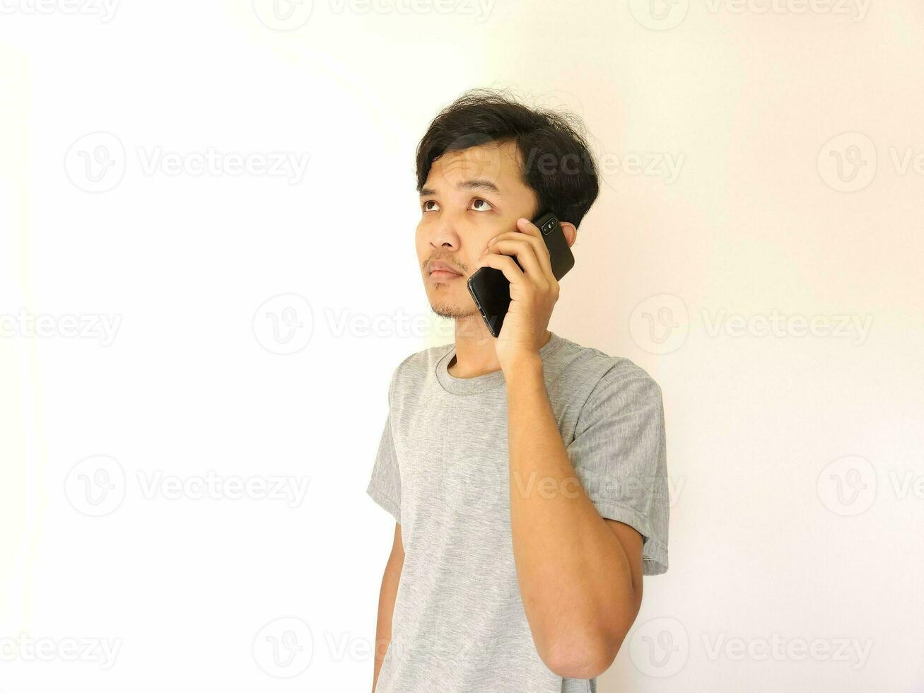 asiático joven hombre en el teléfono con un teléfono inteligente aislado en blanco foto