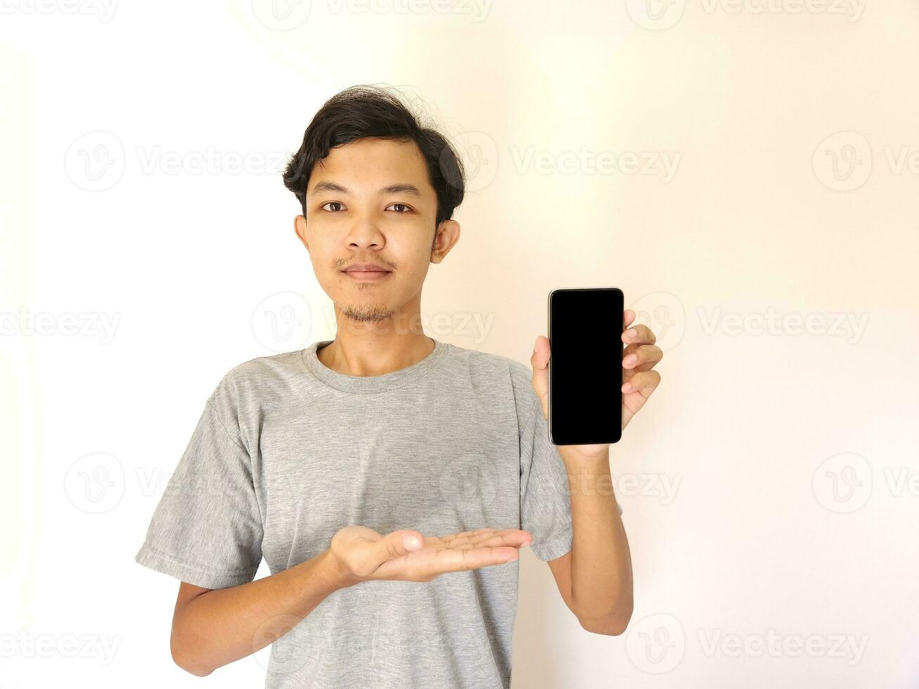 Asian young man showing smartphone with blank screen photo