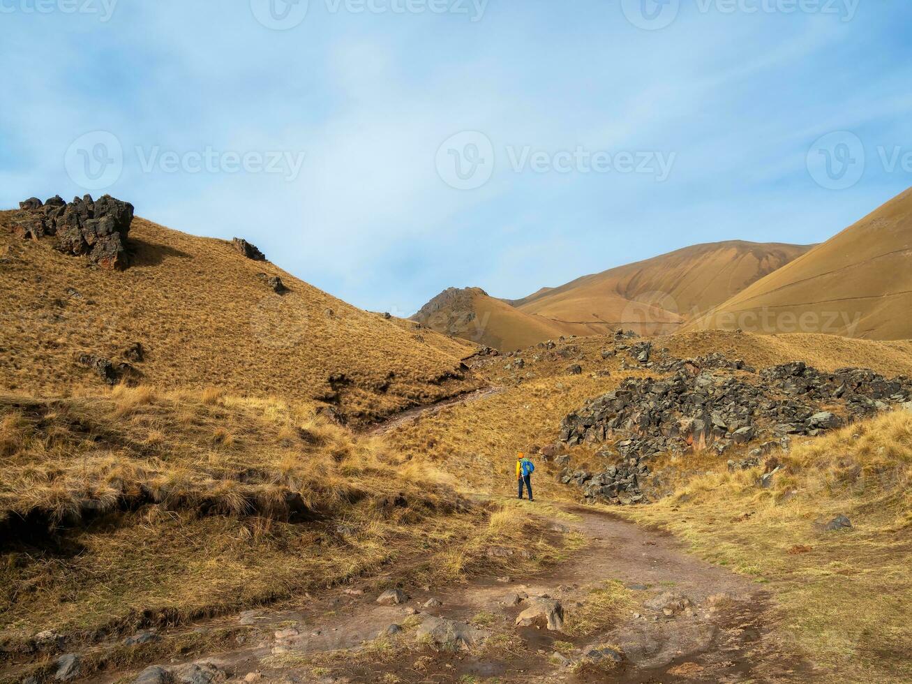 Solo trekking in the Caucasus mountain. Man with a backpack is climbing heavily on a mountain trail. Adventure solo traveling lifestyle concept, active weekend vacation on the wild nature. photo