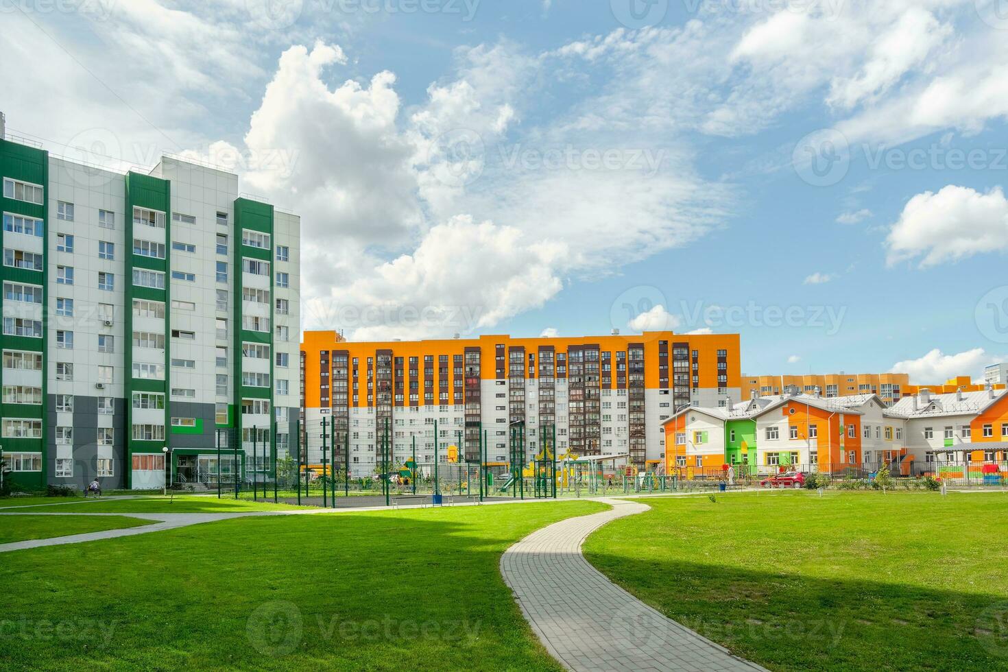 Green courtyard of a modern new building, a tiled alley through a green lawn. Childrens Playground in the courtyard of a new residential area. photo