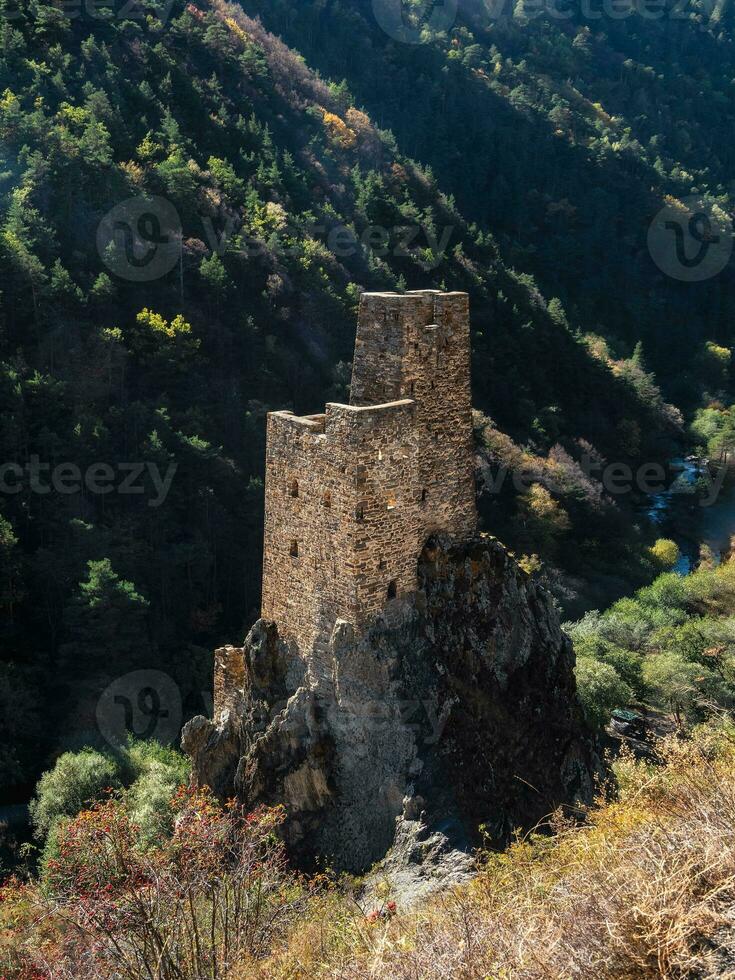 difícil de alcanzar antiguo batalla torres en el rocas soleado tarde en el Cáucaso montañas. medieval torre en verde montaña bosque antecedentes. ingushetia región. foto