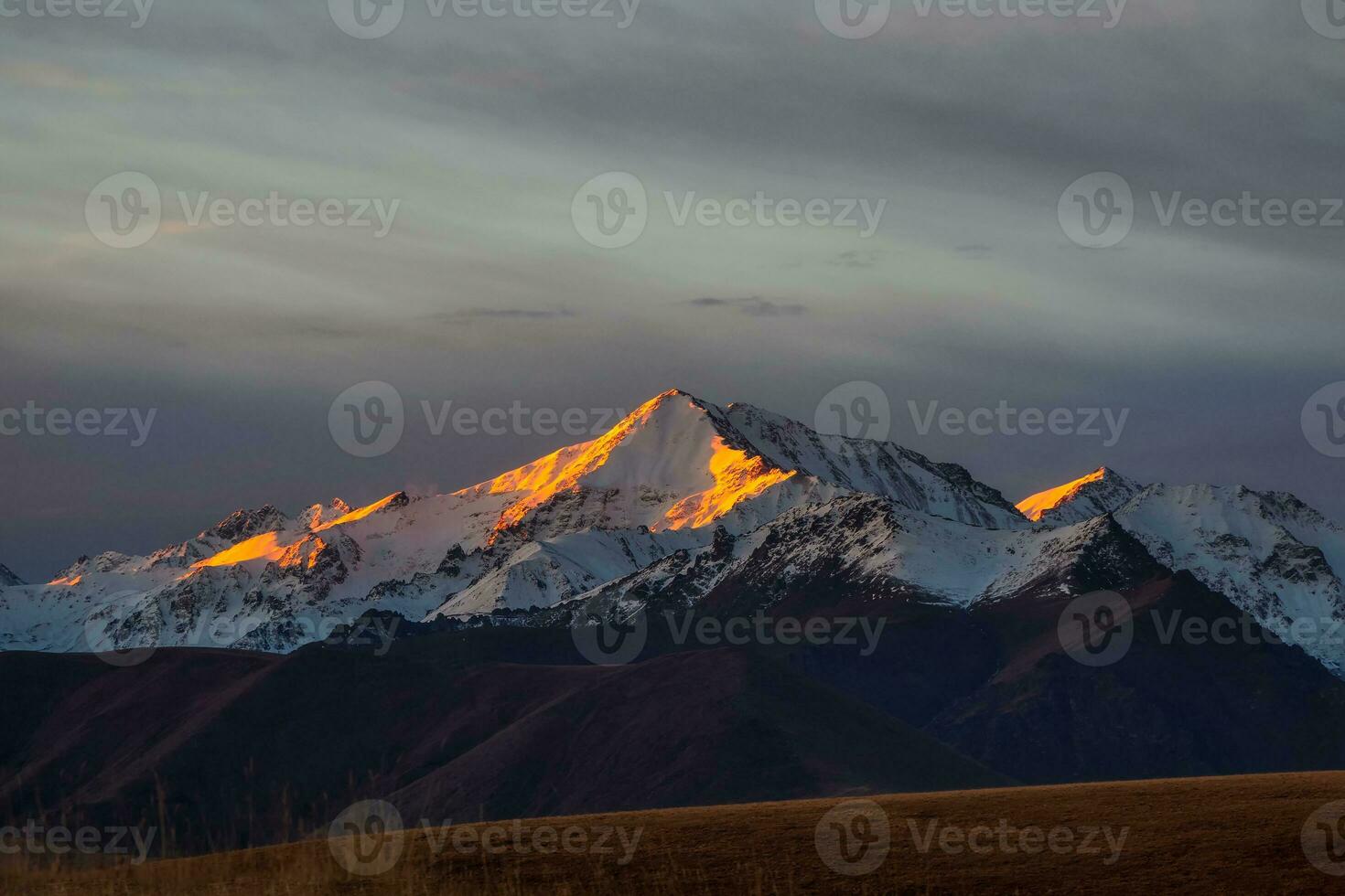 The first rays of the dawn sun on the snowy mountain peaks. Atmo photo