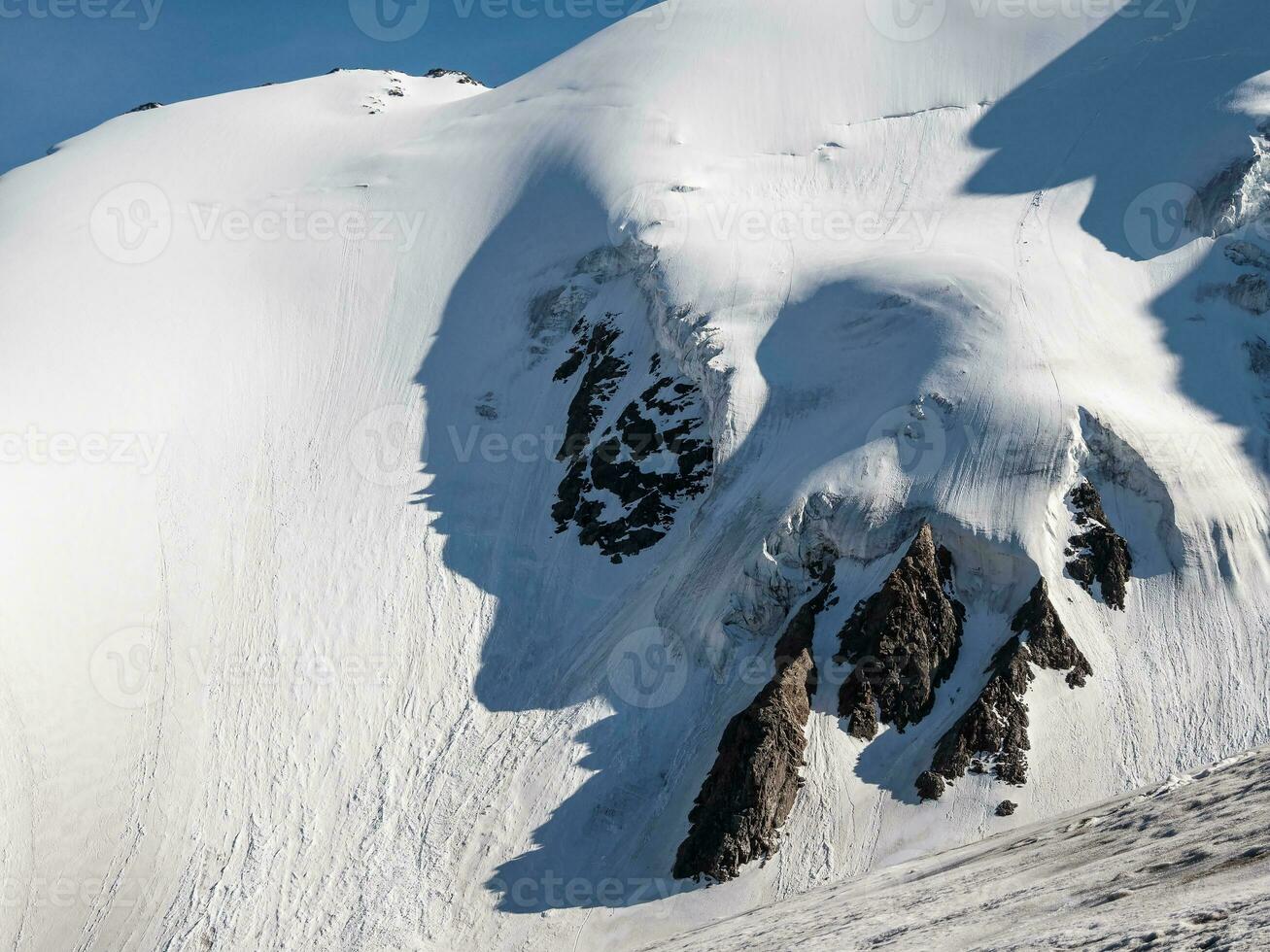 minimalista nieve montaña paisaje con grande glaciar en luz de sol. sencillo Nevado minimalismo con glacial en luz solar. mínimo alpino ver a nieve montaña tapas en soleado día. foto