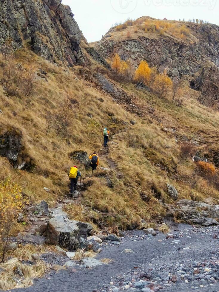 Group of tourists with backpacks climbs the mountains along the autumn trail. photo