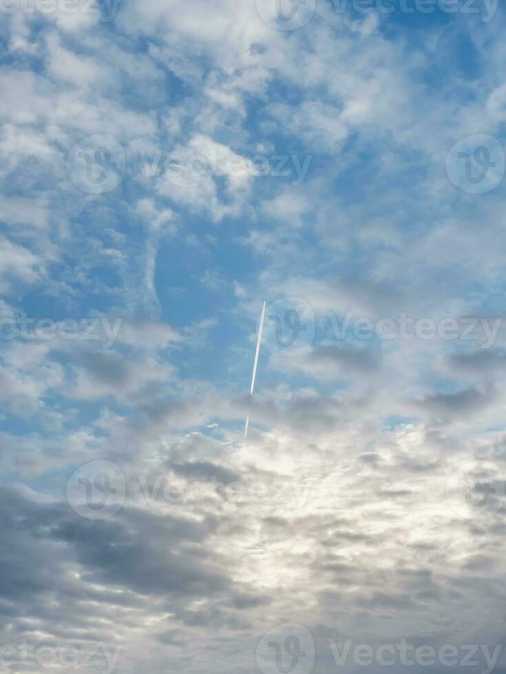 Jet military plane flies through clouds in a blue sky. Vertical view. photo