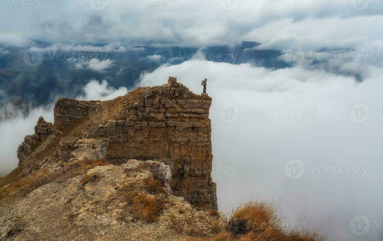 Tourist walks on mountain near abyss edge on high altitude under photo
