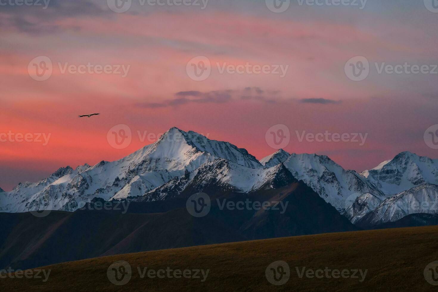 Snowy mountain peaks at dawn. Purple sunset over majestic mountains. Sunset in magenta tones. Atmospheric purple landscape with a high-altitude snowy mountain valley. photo