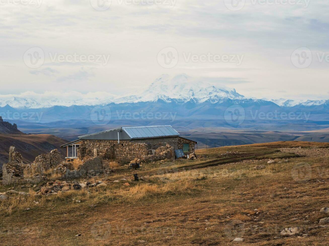 un antiguo Roca invitado casa alto en el montañas en contra el fondo de Nevado majestuoso picos difícil natural condiciones de vivo en el montañas, pobre vida. foto