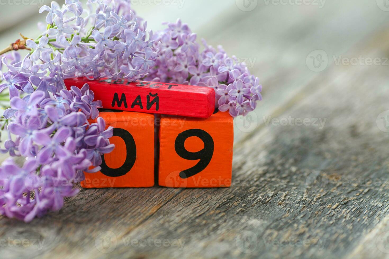 Wooden calendar with Russian text May 9 and a bouquet of lilacs on a wooden background. Victory Day. Copy space. photo