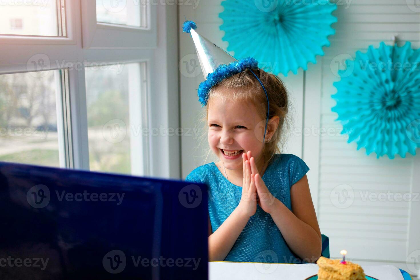 Little happy girl claps her hands, celebrates birthday via the internet in quarantine time, self-isolation and family values, online birthday photo
