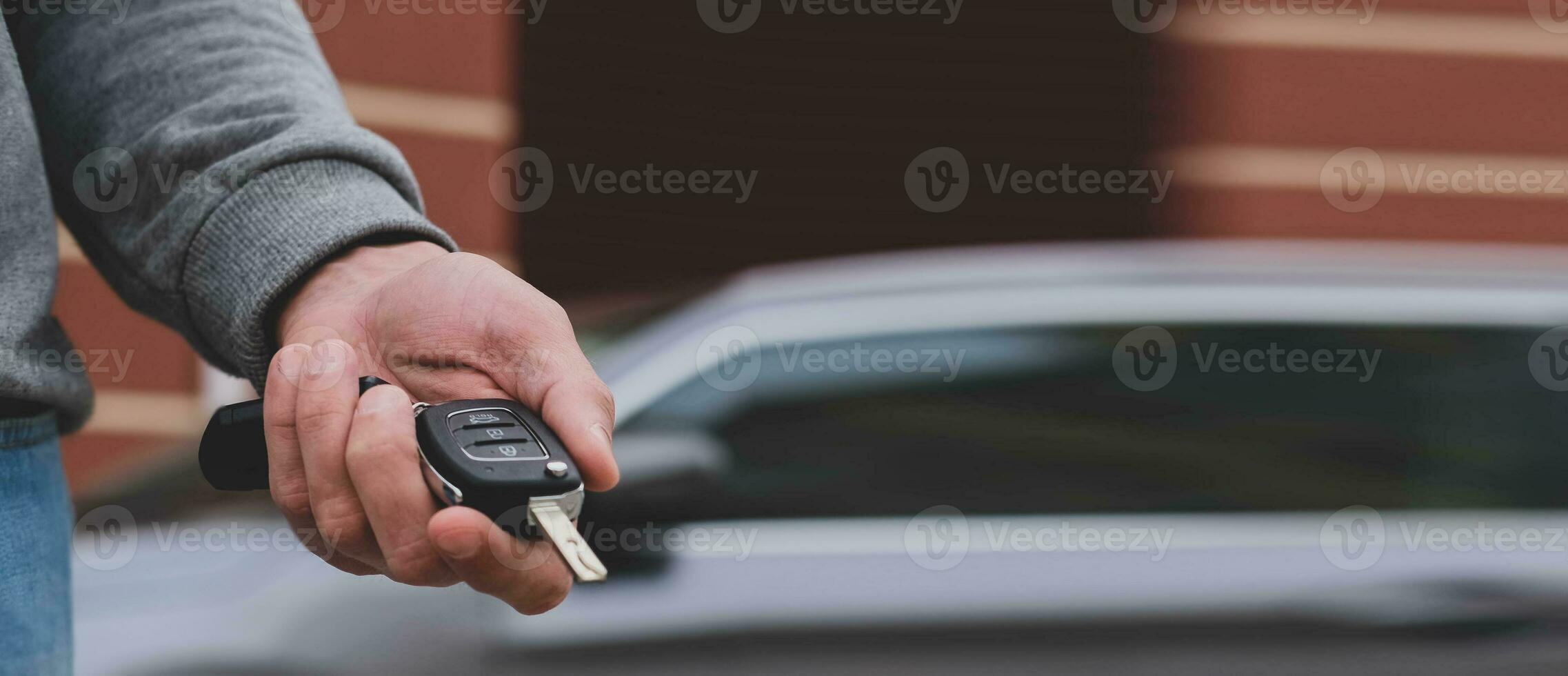 Man in front of the new car and holding keys. Salesman is carrying the car keys delivered to the customer at the showroom .  Rent, credit, insurance, car purchase. Copy space. Banner. photo