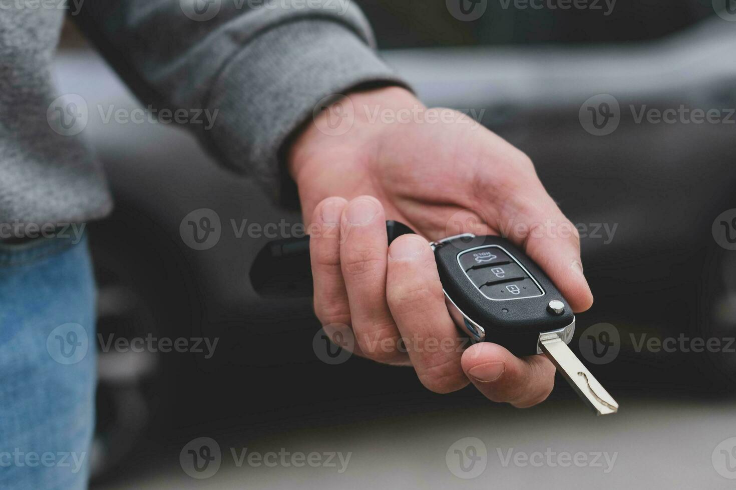 Man in front of the new car and holding keys. Salesman is carrying the car keys delivered to the customer at the showroom with a low interest offer.  Rent, credit, insurance, car purchase. Copy space photo