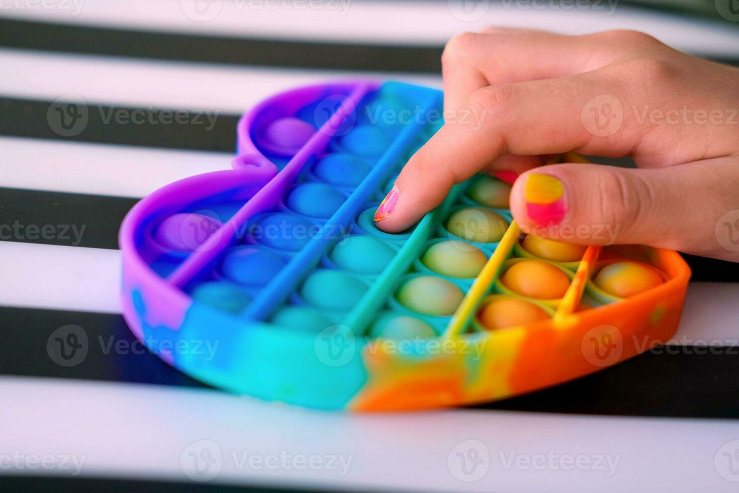 niño jugando con arco iris popular eso agitarse juguete. empujar burbuja agitarse sensorial juguete - lavable y reutilizable silicio estrés alivio juguete. anti estrés juguete para niño con especial necesidades. foto