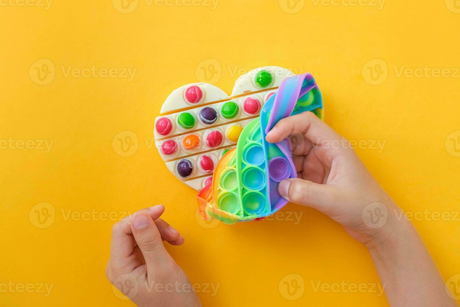Children is  hands take out the prepared chocolate with their own hands from the popit silicone mold. Use the popular pop it toy as a chocolate mold. Step-by-step photo instructions. Step 8.