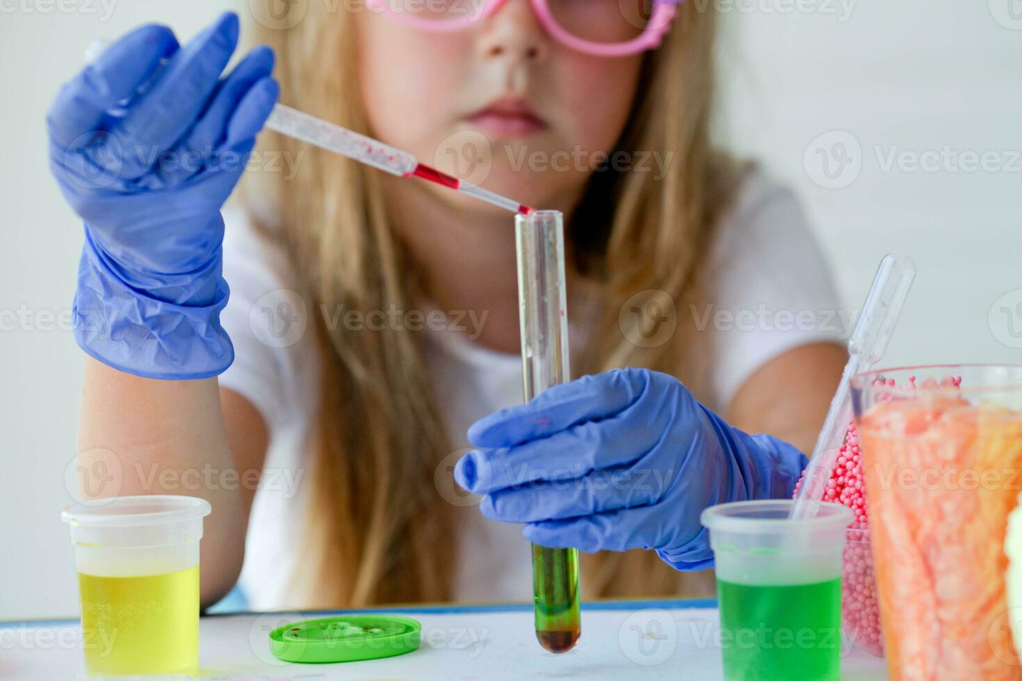 The child conducts experiments. Connects in test tubes fluids of different colors. Close up photo