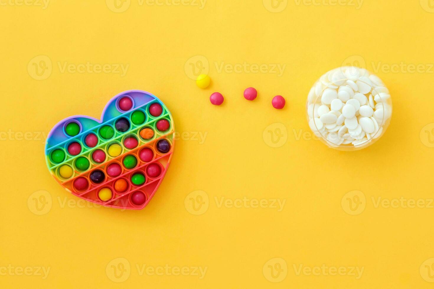 Use the popular pop it toy as a chocolate mold. Colorful candies lie in a silicone form in the form of a popit heart on a yellow background. DIY concept. Step-by-step photo instructions. Step 3.