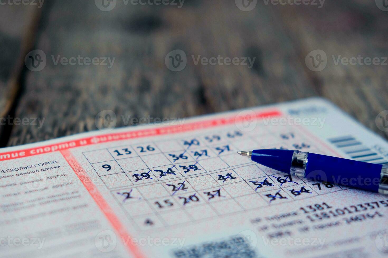 Filled lottery ticket with a pen on a wooden background. photo