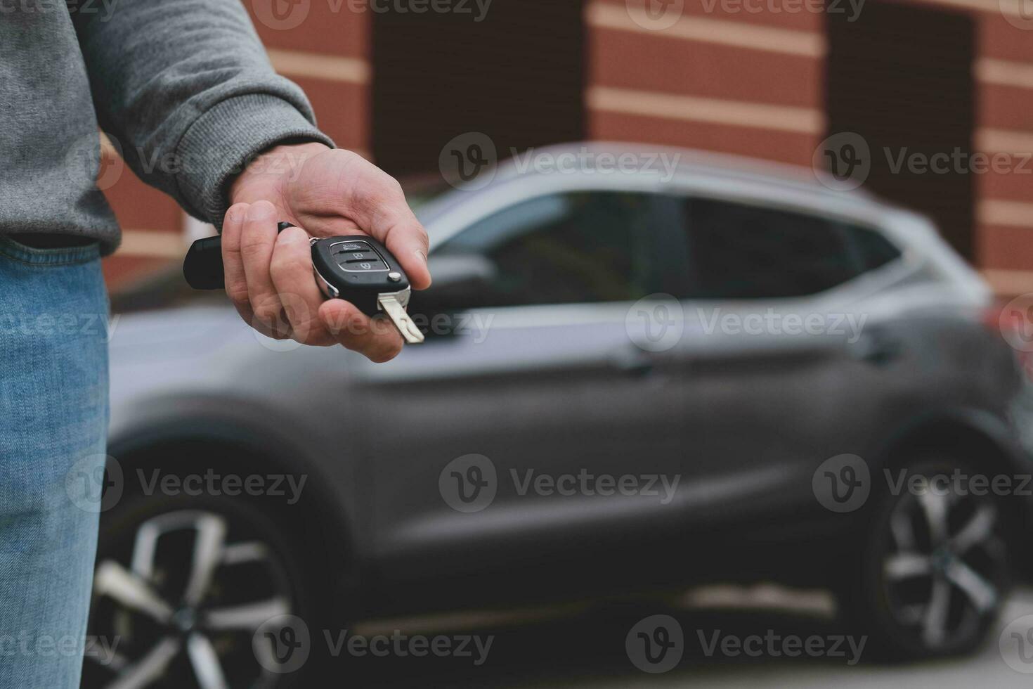 Man in front of the new car and holding keys. Salesman is carrying the car keys delivered to the customer at the showroom with a low interest offer.  Rent, credit, insurance, car purchase. Copy space photo