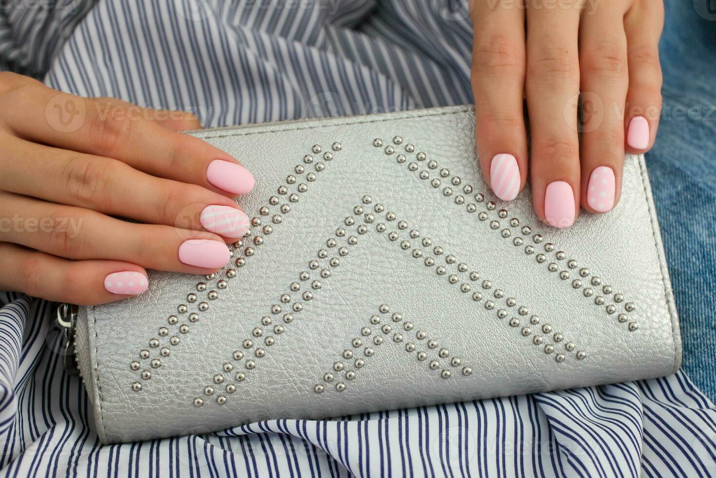 Beautiful pink matte manicure against on the background of a gray bag. Gel silk, oval-shaped nails. photo