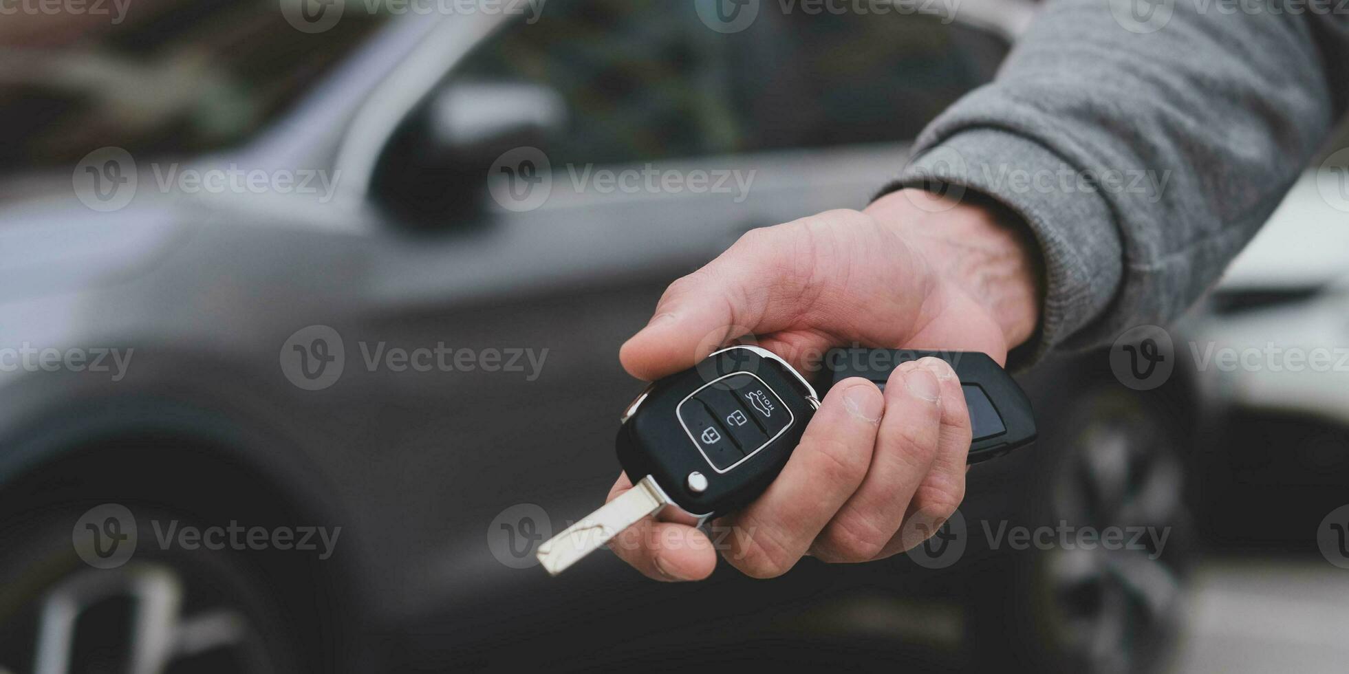 Man in front of the new car and holding keys. Salesman is carrying the car keys delivered to the customer at the showroom .  Rent, credit, insurance, car purchase. Copy space. Banner. photo