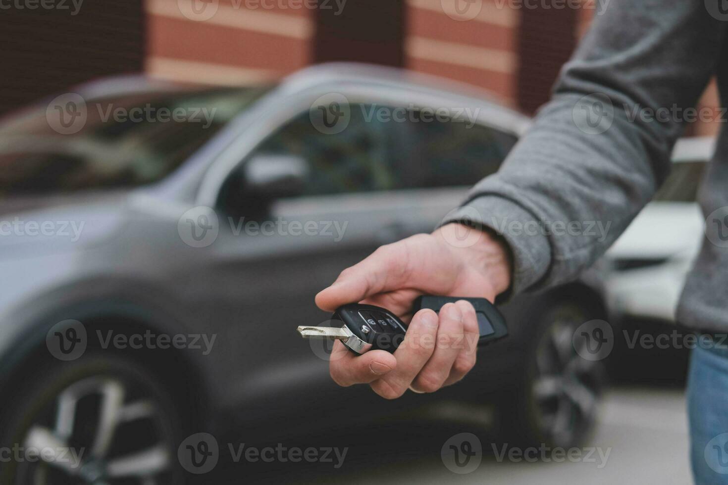 Man in front of the new car and holding keys. Salesman is carrying the car keys delivered to the customer at the showroom with a low interest offer.  Rent, credit, insurance, car purchase. Copy space photo