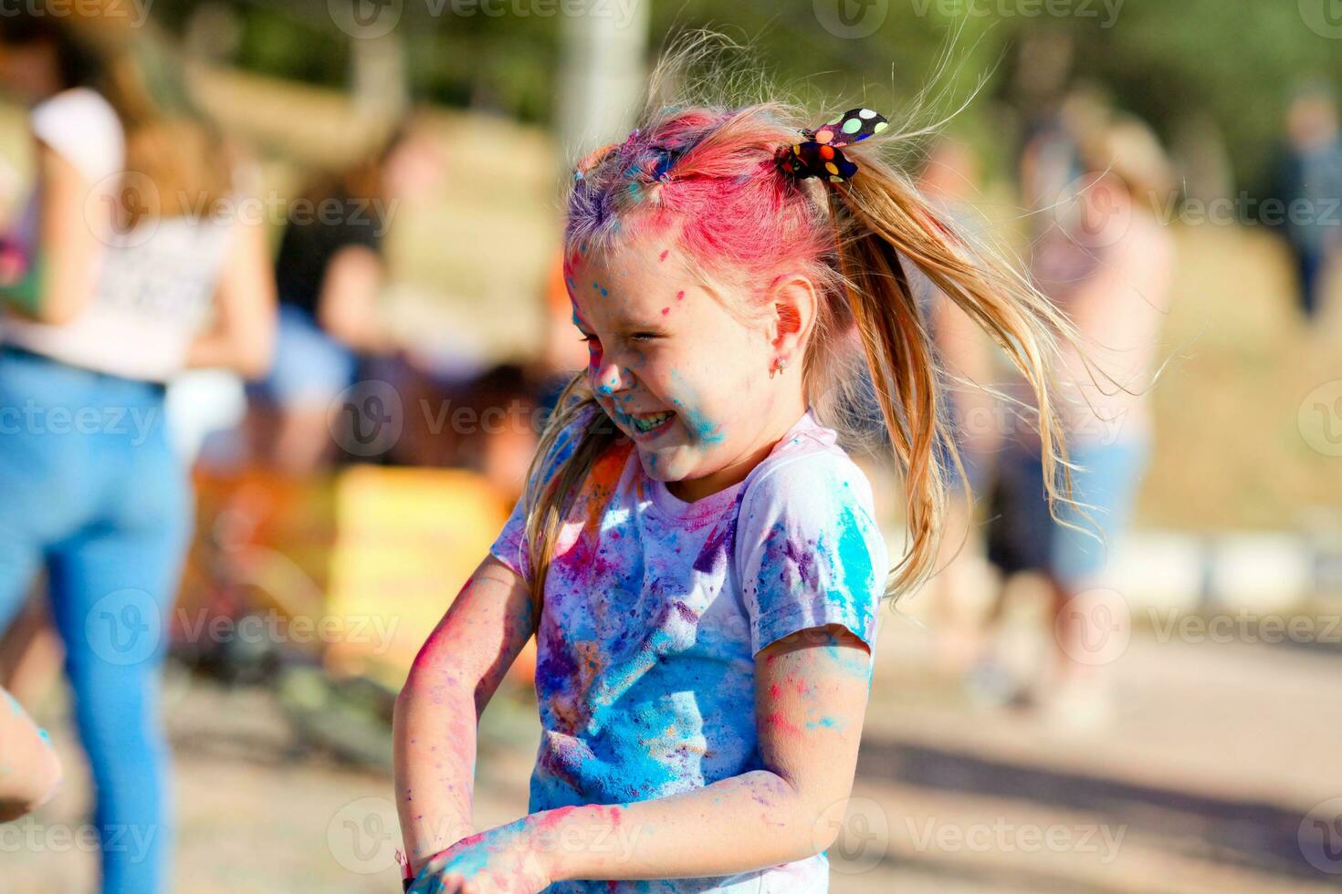 Child in green colors Holi. Holi facial shot on spring color festival of Holi. Holi celebration concept. The portrait laughs the girl  at paint party photo