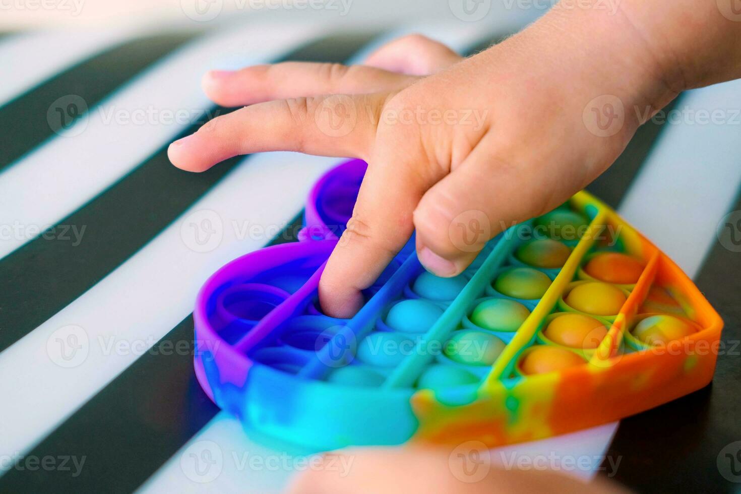 niño jugando con arco iris popular eso agitarse juguete. empujar burbuja agitarse sensorial juguete - lavable y reutilizable silicio estrés alivio juguete. anti estrés juguete para niño con especial necesidades. foto