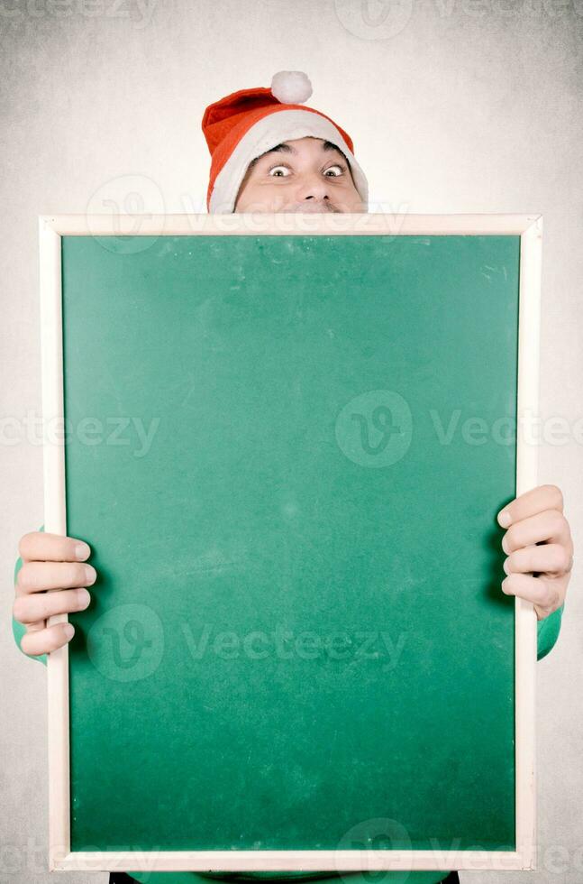 Man holding a blackboard wearing Santa hat photo