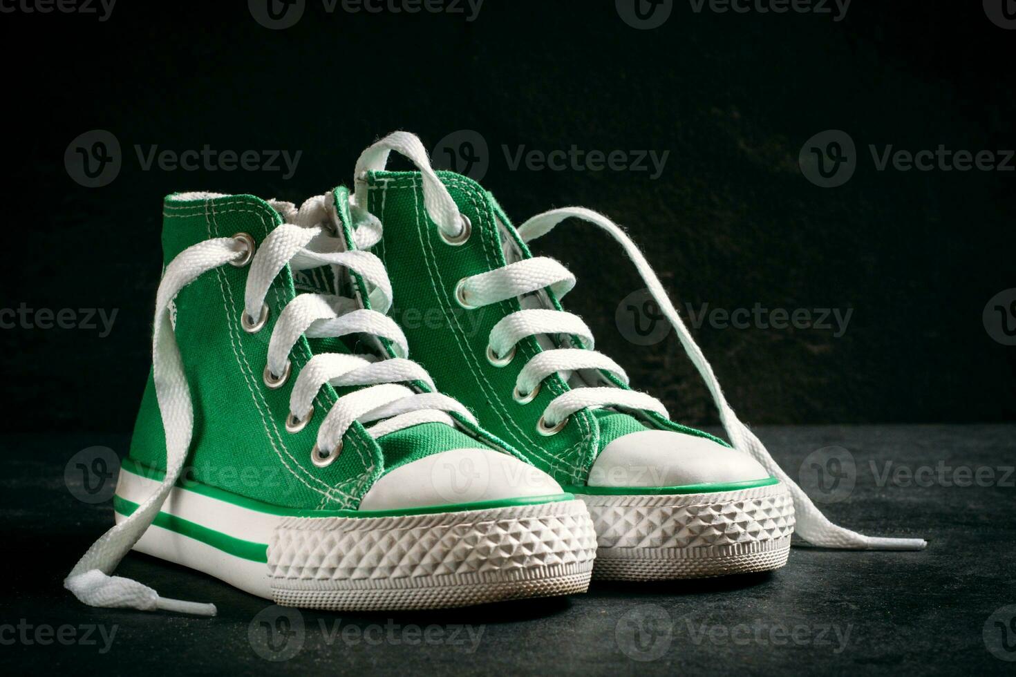 Green sneakers on the black background photo